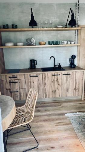 a kitchen with wooden cabinets and a sink and a chair at Apartmán Lipenka in Černá v Pošumaví