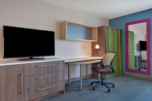 a room with a desk with a tv and a chair at Home2 Suites Williston Burlington, Vt in Williston