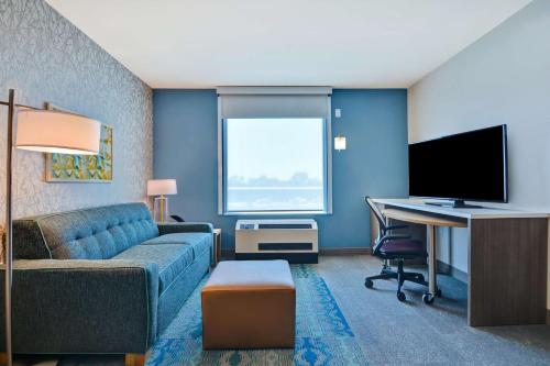 a living room with a couch and a desk with a television at Home2 Suites Williston Burlington, Vt in Williston