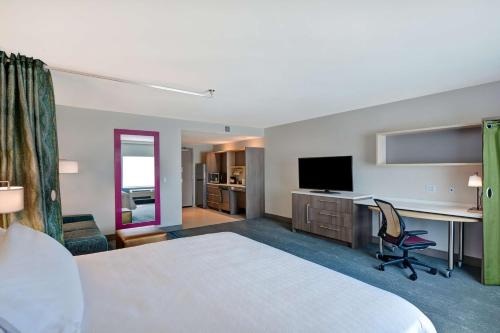 a hotel room with a bed and a desk and a television at Home2 Suites Williston Burlington, Vt in Williston