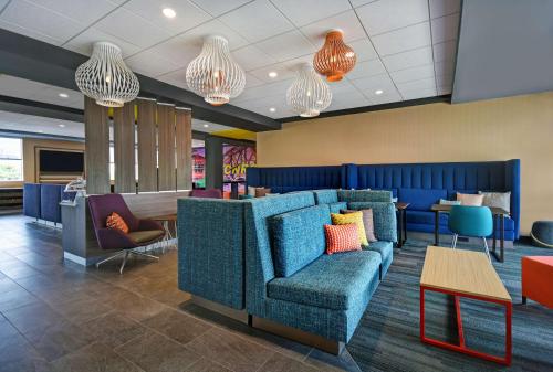 a lobby with a blue couch and tables and chandeliers at Tru By Hilton Monroe, MI in Monroe