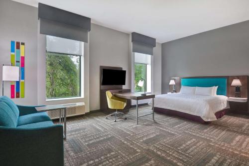 een slaapkamer met een bed, een bureau en een televisie bij Hampton Inn & Suites Tampa Riverview in Tampa