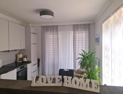 a living room with a love home sign in front of a kitchen at Traumoase in Timmendorfer Strand in Timmendorfer Strand
