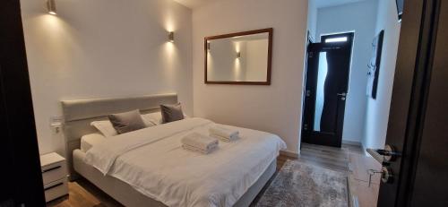 una camera da letto con un letto con lenzuola bianche e uno specchio di MODERN House a Sighetu Marmaţiei