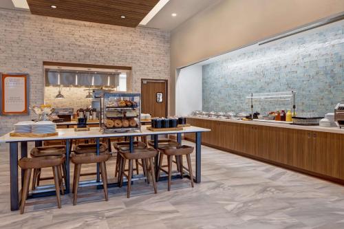 Un restaurante con un mostrador con taburetes y una mesa con comida. en Hilton Garden Inn Summerville, Sc, en Summerville