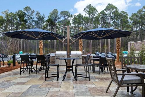 a patio with tables and chairs and umbrellas at Homewood Suites By Hilton Summerville in Summerville