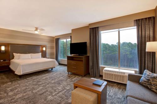 Homewood Suites By Hilton Summerville في سامرفيل: غرفة فندقية بسرير ونافذة كبيرة