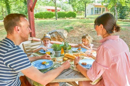 une famille assise sur une table de pique-nique pour manger dans l'établissement FranceComfort - L'Espinet, à Quillan