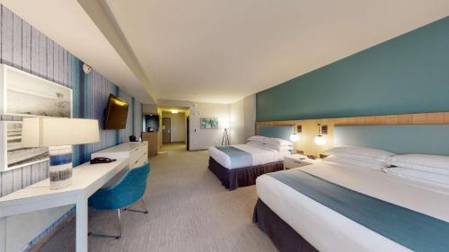 a hotel room with two beds and a desk at SunCoast Hotel Anaheim, Tapestry Collection by Hilton in Anaheim