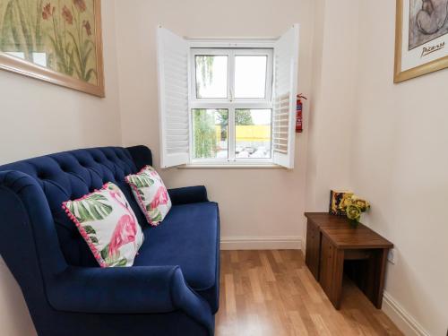 a blue couch in a living room with a window at 1 Cockerill Fold in Beverley