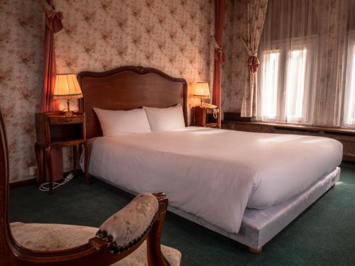 a bedroom with a large bed and a chair at Château Des Bondons EI in La Ferté-sous-Jouarre