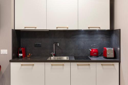 a kitchen with white cabinets and a sink and red appliances at Emerald Suites in Stresa