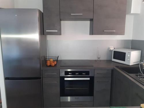 une cuisine avec un réfrigérateur en acier inoxydable et un micro-ondes dans l'établissement Jolie 2P au centre de golfe-juan à 2mn des plages, à Vallauris
