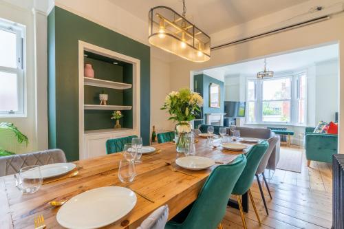 a dining room with a wooden table and green chairs at Otley House in Cheltenham
