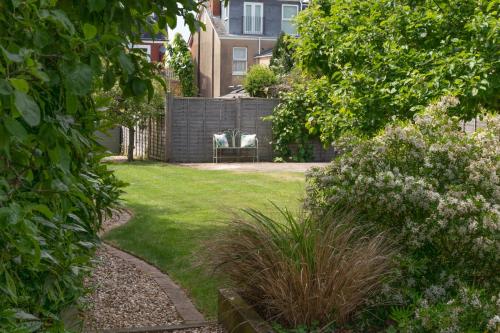 un jardín con una valla y sillas en un patio en Otley House en Cheltenham