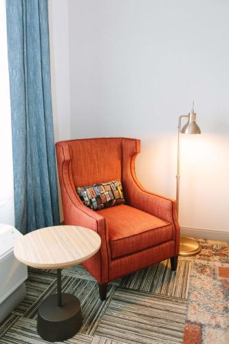 a living room with an orange chair and a table at Hilton Garden Inn Winter Park, FL in Orlando
