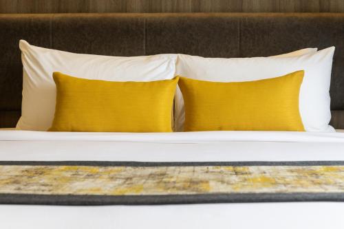 two pillows on a bed with two yellow pillows at Bandalo Boutique Hotel - Patong Beach Road in Patong Beach