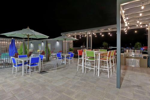a patio with tables and chairs and umbrellas at night at Home2 Suites By Hilton Buckeye Phoenix in Buckeye