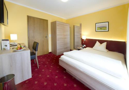 a hotel room with a large white bed and a desk at Hotel Bruno in Fügen