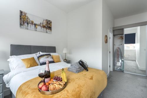 a bed with a bowl of fruit and a bottle of wine at Deluxe 2 bed, 2 bathroom Milton Keynes apartment within walking distance to train station and City centre. in Milton Keynes