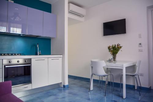 a kitchen with white cabinets and a white table and chairs at Casa Vacanze Baia Garagliano in Scario