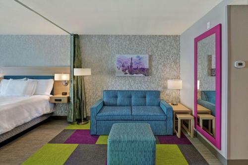 Habitación de hotel con cama y silla azul en Home2 Suites By Hilton Buckeye Phoenix, en Buckeye