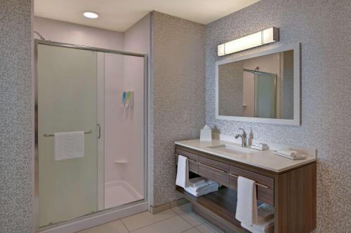 a bathroom with a sink and a shower with a mirror at Home2 Suites By Hilton Buckeye Phoenix in Buckeye