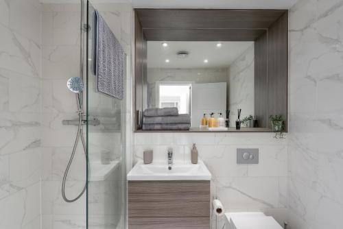 uma casa de banho com um chuveiro, um lavatório e um espelho. em Deluxe 2 bed, 2 bathroom Milton Keynes apartment within walking distance to train station and City centre. em Milton Keynes