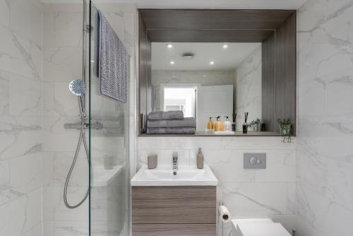 a bathroom with a shower and a sink and a mirror at Deluxe 2 bed, 2 bathroom Milton Keynes apartment within walking distance to train station and City centre. in Milton Keynes