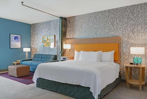 特雷西Home2 Suites By Hilton Tracy, Ca的卧室里有一张大床和一张蓝色沙发