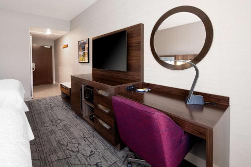 a hotel room with a desk with a mirror and a bed at Hampton Inn & Suites Gilroy, Ca in Gilroy