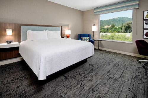 Habitación de hotel con cama grande y ventana en Hampton Inn & Suites Gilroy, Ca en Gilroy