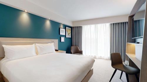 a hotel room with a bed and a blue wall at Hampton By Hilton Manchester Northern Quarter in Manchester