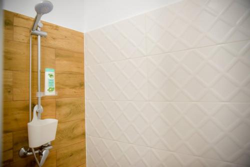 La salle de bains est pourvue d'une douche et d'un mur en carrelage blanc. dans l'établissement Silent House Sovata, à Sovata