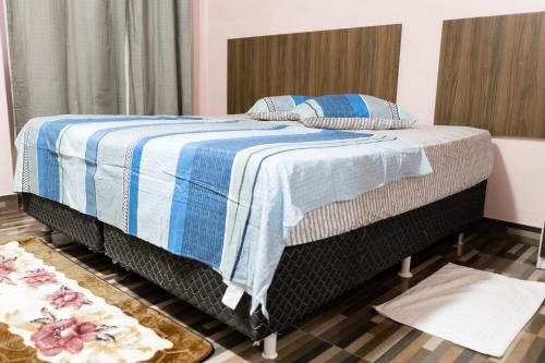 a bedroom with a bed with a blue and white blanket at Guajará Palace Hotel in Porto Velho