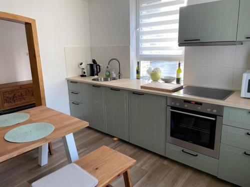 cocina con armarios grises, mesa y fregadero en Ferienwohnung KORS en Winterberg