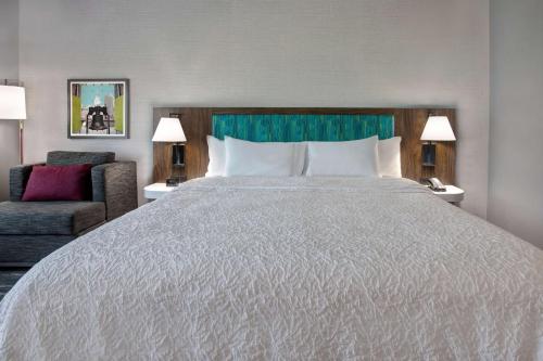 a hotel room with a large bed and a chair at Hampton Inn & Suites Deptford, Nj in Deptford