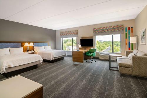 a hotel room with two beds and a desk and a tv at Hampton Inn & Suites Raleigh Midtown, NC in Raleigh
