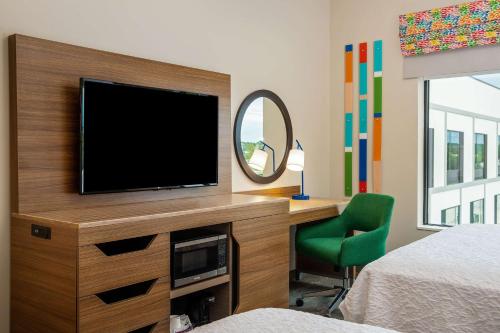 a bedroom with a flat screen tv and a mirror at Hampton Inn & Suites Raleigh Midtown, NC in Raleigh