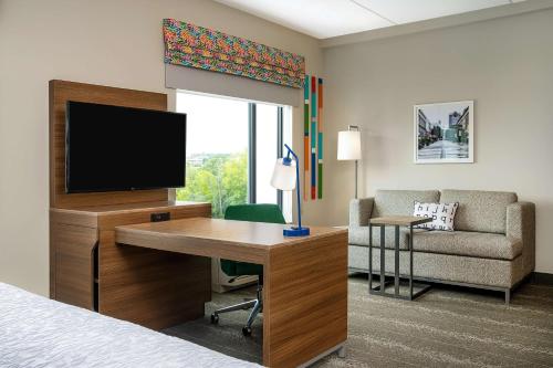 a hotel room with a bed and a desk with a television at Hampton Inn & Suites Raleigh Midtown, NC in Raleigh
