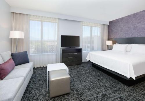 レイクフォレストにあるHomewood Suites By Hilton Irvine Spectrum Lake Forestのベッドとソファ付きの広いホテルルームです。