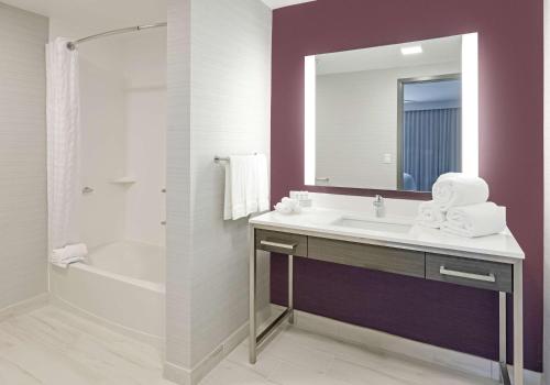 a bathroom with a sink and a tub and a mirror at Homewood Suites By Hilton Irvine Spectrum Lake Forest in Lake Forest