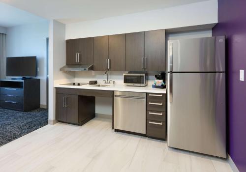 a kitchen with a stainless steel refrigerator and wooden cabinets at Homewood Suites By Hilton Irvine Spectrum Lake Forest in Lake Forest