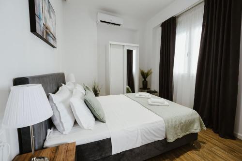 Schlafzimmer mit einem Bett mit weißer Bettwäsche und Kissen in der Unterkunft M & N Guesthouse in Volos