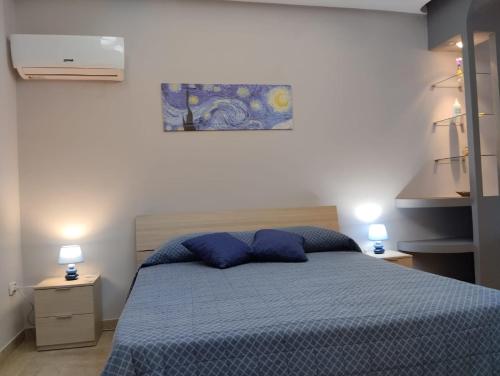 1 dormitorio con 1 cama azul y 2 almohadas azules en Bougainvillea casa vacanza, en Castelbuono