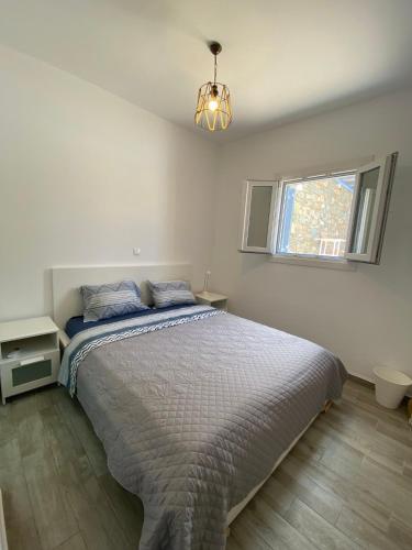 a white bedroom with a bed and a window at Syrona in Posidhonía