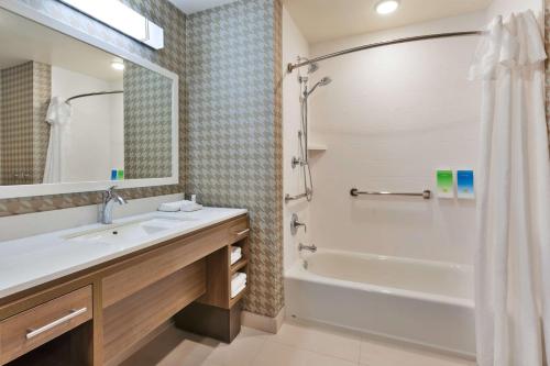 y baño con bañera, lavamanos y ducha. en Home2 Suites By Hilton Battle Creek, Mi, en Battle Creek