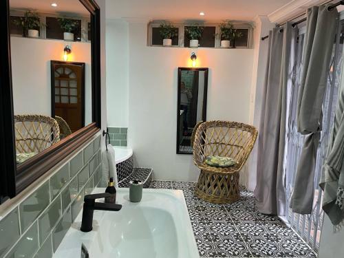 bagno con vasca, sedia e specchio di Nonna's Cottage a Durban
