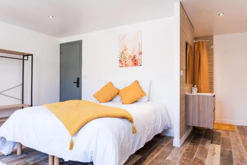 a bedroom with a white bed with yellow pillows at **Auberge de l'Aude** in Carcassonne
