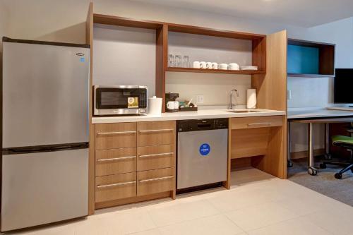a kitchen with a refrigerator and a microwave at Home2 Suites By Hilton Carmel Indianapolis in Carmel